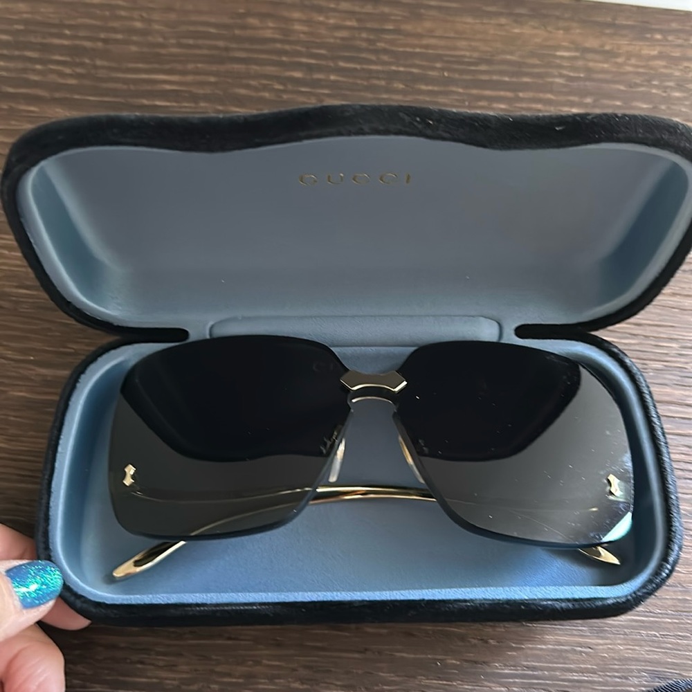Gucci sunglasses. Gold frames and black lenses. Fashionable arm low on the sides